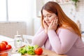 Gloomy sad plump woman looking at vegetables