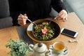 Vegan girl dines in a cafe. A healthy lunch of veggie salad topped with fresh strawberries.