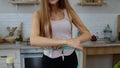 Vegan girl in kitchen. Girl measuring with tape measure her slim waist. Weight loss, diet lifestyle