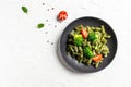 Vegan green pasta with broccoli, avocado sauce, spinach leaves and cherry tomatoes on liht background. Vegetarian healthy food.