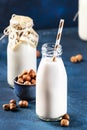 Vegan Hazelnut nut milk in bottles, closeup, blue table background. Non dairy alternative milk. Healthy vegetarian food and drink