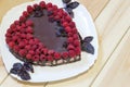 Vegan heart shaped chocolate cake with raspberries on light wooden table with copy space. Sweet present for lovers Royalty Free Stock Photo