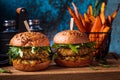 Vegan lentil burger with arugula, mustard sauce, fresh vegetables and sweet potato fries on wooden board, blue background. Vegan Royalty Free Stock Photo