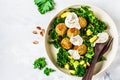 Vegan lentils meatballs with green kale salad, avocado and tahini dressing in a white dish, top view