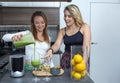 Cute vegan lesbian couple, preparing spinach smoothie. LGTB concept, vegan people