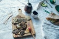 Vegan linnen crackers on a wooden board together with calabash, saucer, plate, cutlery lieing on a rough linnen fabric