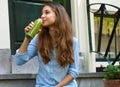 Vegan meal and detox break time concept. Beautiful girl sitting outside her home drinking green juice. Healthy detox vegan diet Royalty Free Stock Photo