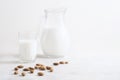 Vegan nut milk and almonds on white wooden background.