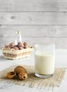 Vegan nut milk in a glass on a burlap and organic walnuts in a basket on a wooden table background, non-dairy alternative milk,