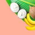 Vegan plant based coconut and banana ice cream in natural material bowls on fresh green palm leaf on pink background Royalty Free Stock Photo