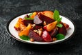 Vegan Plum, beet salad with pecan nuts, mint and herbs on rustic black table