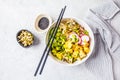 Vegan poke bowl with pickled tofu, vegetables and rice in a white bowl, top view