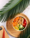 Vegan Poke bowl raw salad, heura soy protein, vegan chicken with variety vegetables, served in bowl on tropical leaves. Top view. Royalty Free Stock Photo