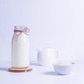Vegan rice milk in a glass bottle and rice in a white plate on a wooden stand