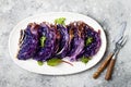 Vegan roasted red cabbage steaks on grey concrete background. Top view, flat lay.