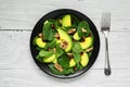 Vegan salad with avocado, spinach, pomegranate and walnuts in black plate with fork. healthy food Royalty Free Stock Photo