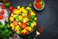 Vegan salad with sweet corn, avocado, jalapeno pepper, red tomatoes, fresh cilantro and olive oil and lime dressing. Black table Royalty Free Stock Photo