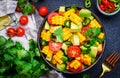 Vegan salad with sweet corn, avocado, jalapeno pepper, red tomatoes, fresh cilantro and olive oil and lime dressing. Black table Royalty Free Stock Photo