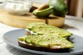 Vegan sandwich, rye bread toast, avocado slices, vegenaise sauce & raw arugula. Toasted sourdough, eggless mayonnaise, wooden tabl