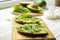 Vegan sandwich, rye bread toast, avocado slices, vegenaise sauce & raw arugula. Toasted sourdough, eggless mayonnaise, wooden tabl Royalty Free Stock Photo