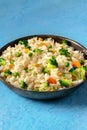 Vegan stir fied rice with vegetables, a close-up in a pan on blue