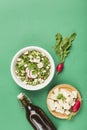 Vegan summer cold soup with tofu, cucumber, radish and fresh herbs in a plate on a green background with a bottle of kvass for Royalty Free Stock Photo