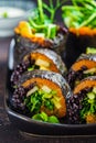 Vegan sushi rolls with black rice, avocado and sweet potato on black dish. Vegan food concept Royalty Free Stock Photo