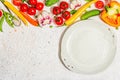 Vegan table setting. Assorted of ripe fresh vegetables, empty plate, cutlery, spices Royalty Free Stock Photo