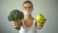 Vegan with taped mouth holds vegetables, concept of severe diet, harm to health