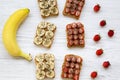 Vegan toasts with peanut butter, fruits and chia seeds on a white wooden table, top view. Some ingredients.