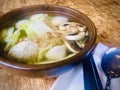 Vege Ball soup in a brown bowl on wooden table.