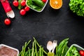 Vegearian lunch. Vegetables tomato, cucumber, asparagus, salad, orange on black background top view copyspace