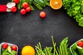 Vegearian lunch. Vegetables tomato, cucumber, asparagus, salad, orange on black background top view copyspace