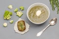 Vegetable broccoli puree soup in white bowl. Spoon next to bowl. Bruschetta on paper. Brussels sprouts and romanescu cabbage