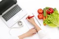 Vegetable diet nutrition or medicaments concept. Doctors hands writing diet plan, ripe vegetable composition, laptop and measuring Royalty Free Stock Photo