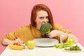 Vegetable diet. Sad dull woman holding broccoli on fork while making grimace Royalty Free Stock Photo