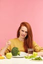 Vegetable diet. Sad dull woman holding broccoli on fork while making grimace Royalty Free Stock Photo