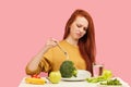 Vegetable diet. Sad dull woman holding broccoli on fork while making grimace Royalty Free Stock Photo