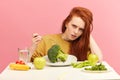 Vegetable diet. Sad dull woman holding broccoli on fork while making grimace Royalty Free Stock Photo