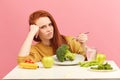 Vegetable diet. Sad dull woman holding broccoli on fork while making grimace