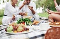 Vegetable food is on the table. Group of adult friends have a rest and conversation in the backyard of restaurant at Royalty Free Stock Photo