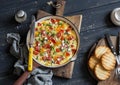 Vegetable frittata in a cast iron skillet on wooden background. Delicious brunch