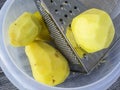 Vegetable grater and peeled potatoes ready to be shredded Royalty Free Stock Photo