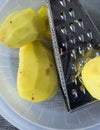 Vegetable grater and peeled potatoes ready to be shredded Royalty Free Stock Photo