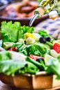 Vegetable lettuce salad. Olive oil pouring into bowl of salad. Italian Mediterranean or Greek cuisine. Vegetarian vegan food Royalty Free Stock Photo