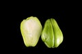 Chayote delicious green vegetable, cut in half, close-up, on black background