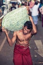 Vegetable market. Worker with heavy sack.