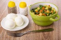 Vegetable mix from green bean, green peas, potato, onion, carrot in bowl, salt, pepper shaker, boiled eggs in saucer, fork on