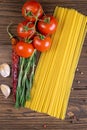 Vegetable pasta ingredients: spaghetti, peppers, tomatoes, basil, rosemary, olive oil, garlic, sea salt and spices on a dark Royalty Free Stock Photo