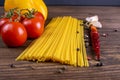 Vegetable pasta ingredients: spaghetti, peppers, tomatoes, basil, rosemary, olive oil, garlic, sea salt and spices on a dark Royalty Free Stock Photo